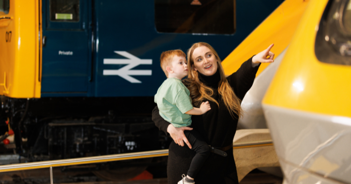 Woman holding small boy pointing at engines inside Locomotion Museum. Credit Locomotion Shildon.